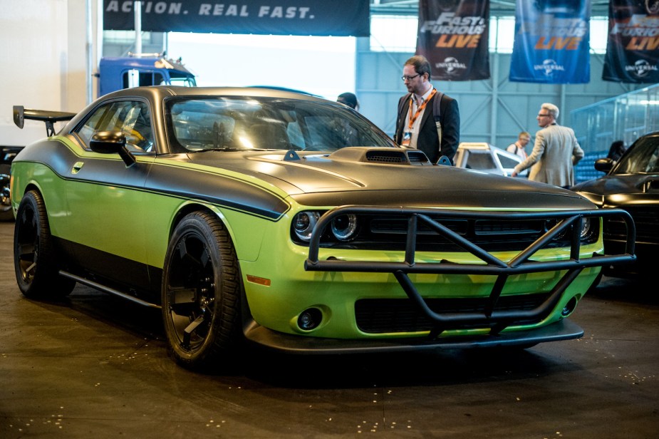 A neon green Challenger from the Fast and Furious movie is parked in a museum of other movie cars.