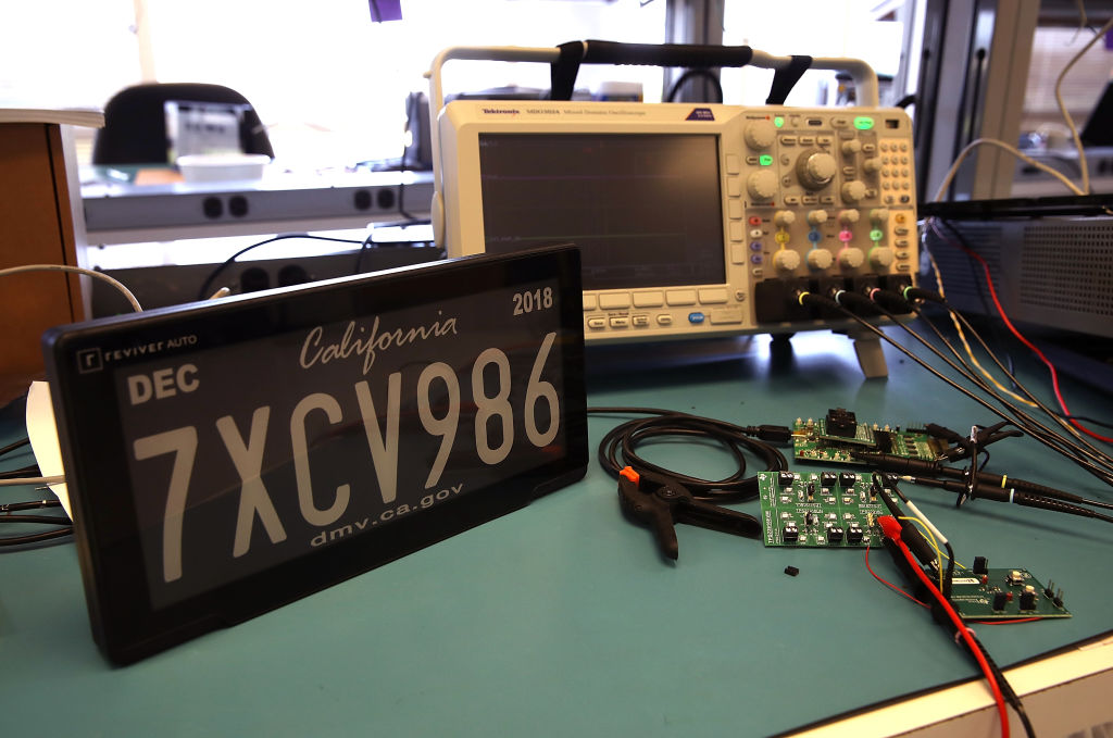 A black digital license plate being worked on in a computer lab.