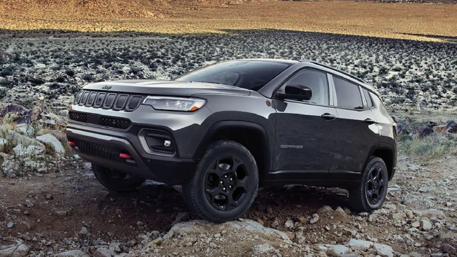 Gray 2023 Jeep Compass small SUV, the most affordable new Jeep, driving on rocky terrain