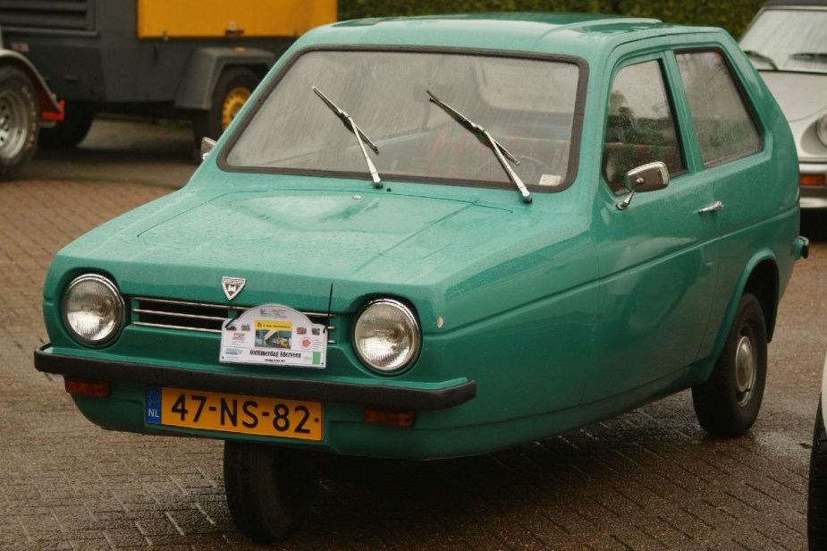 Green Reliant Robin parked. This is easily one of the ugliest cars ever made.