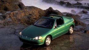 A green Honda Del Sol showing off its targa top option in a scenic natural area