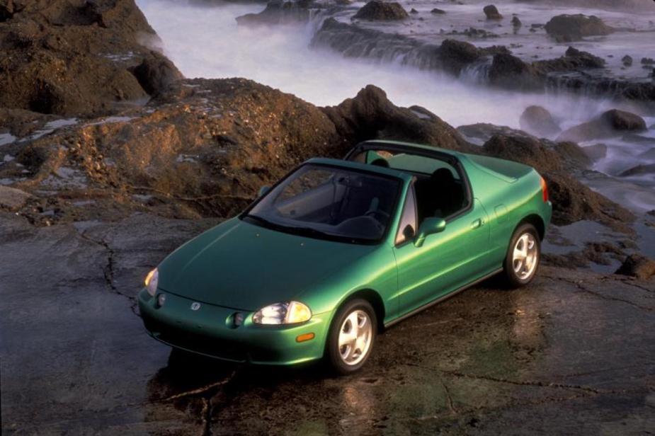 A green Honda Del Sol showing off its targa top option in a scenic natural area