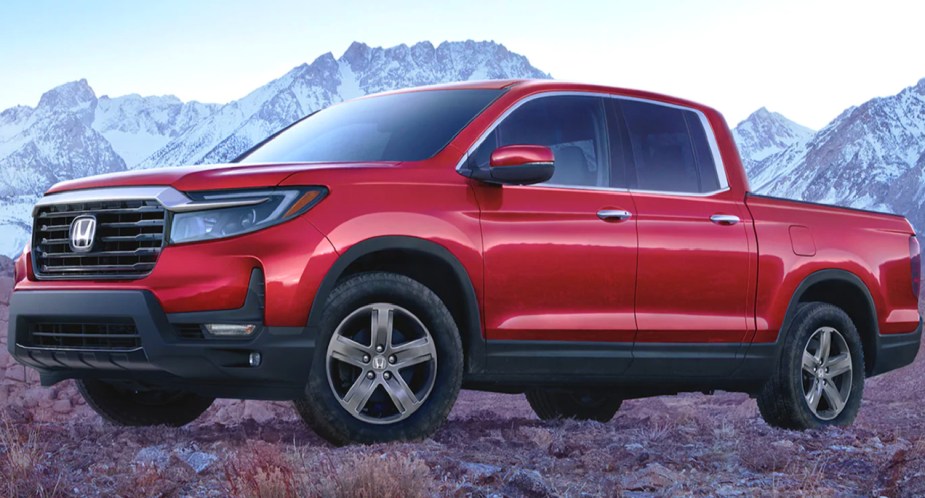 A red 2023 Honda Ridgeline midsize pickup truck is parked outdoors. 