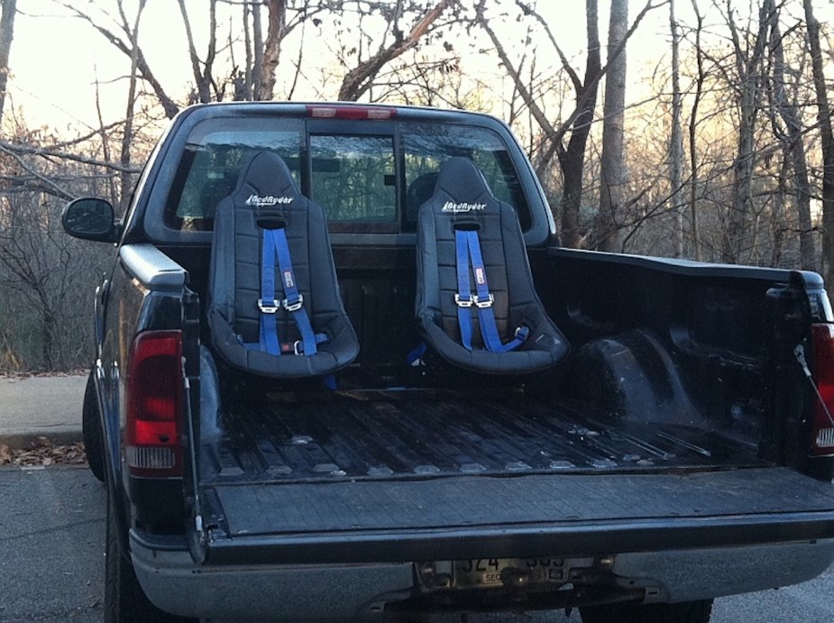 Jump seats by BedRyder installed in the bed of a pickup truck, complete with harness style seat belts.