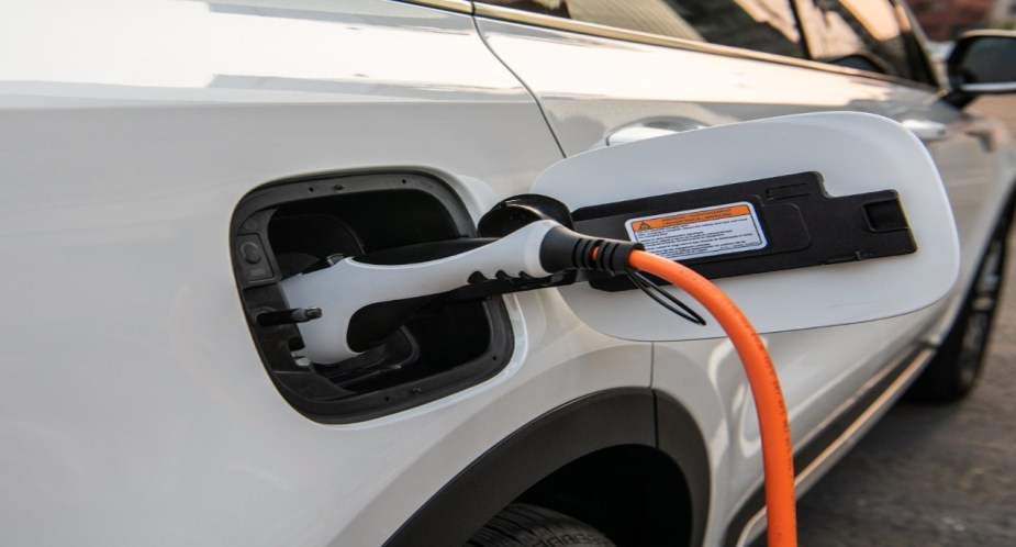 A white Kia Sorento Plug-In Hybrid midsize plug-in hybrid SUV being charged. 