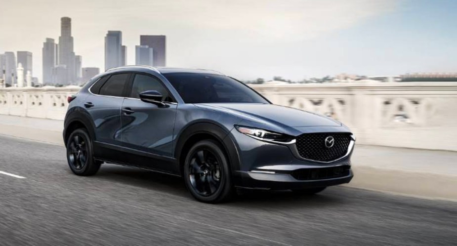 A gray 2023 Mazda CX-30  subcompact SUV is driving on the road. 
