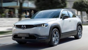 A gray 2023 Mazda MX-30 subcompact SUV is driving on the road.