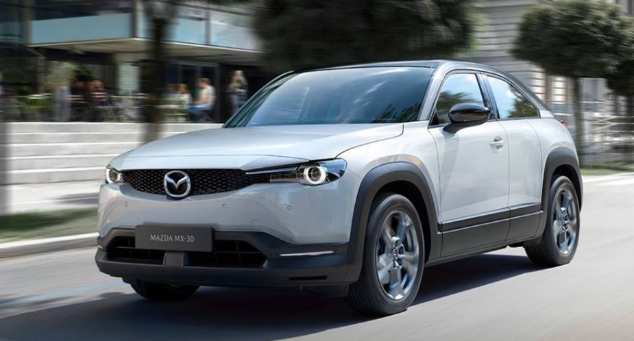 A gray Mazda CX-30 subcompact electric SUV is driving on the road. 