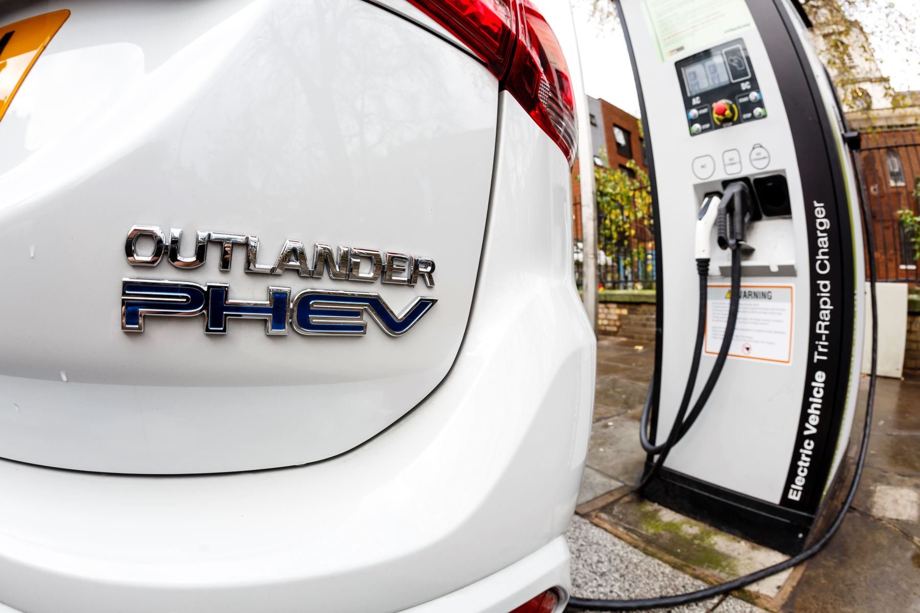A Mitsubishi Outlander PHEV plugged into a charging station on a London street