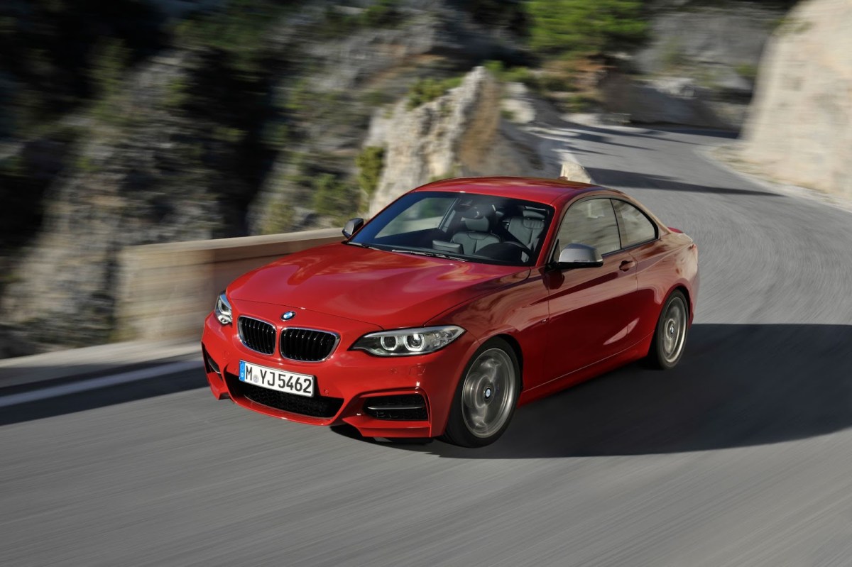 A red BMW M235i on a twisty mountain road