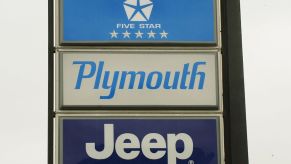 A Chrysler, Plymouth and Jeep sign outside a car dealership.
