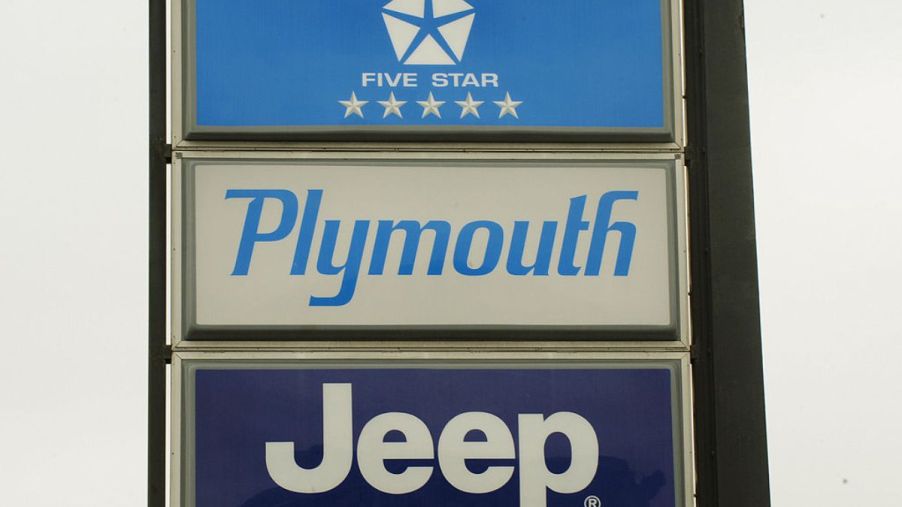 A Chrysler, Plymouth and Jeep sign outside a car dealership.