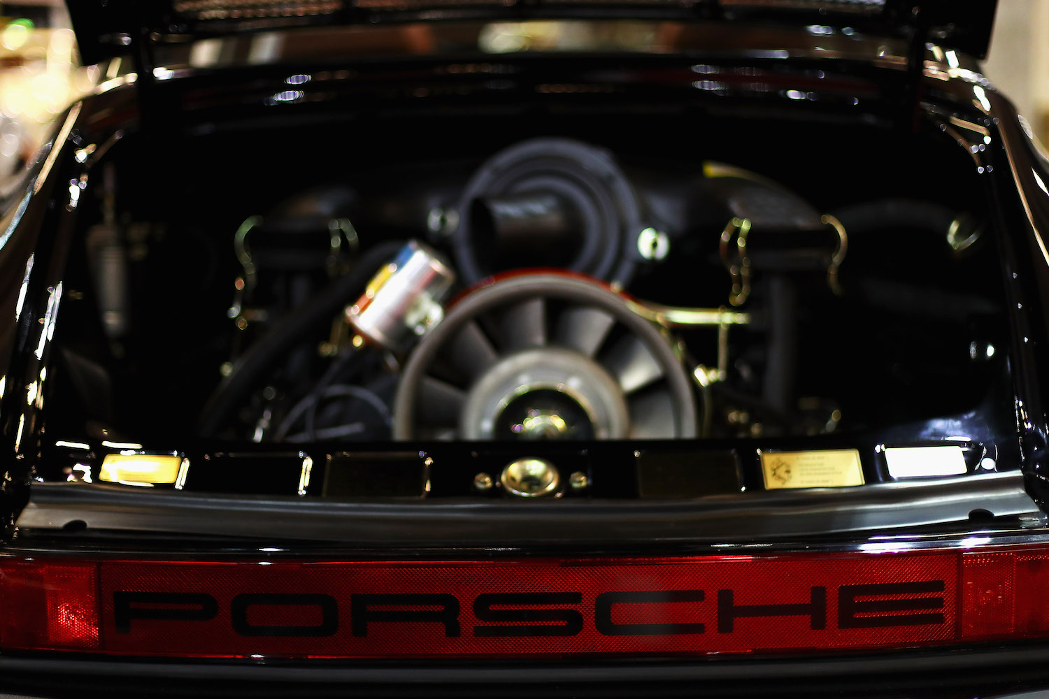 Closeup of the engine bay of a black Porsche 911 with its air cooled flat-six engine.