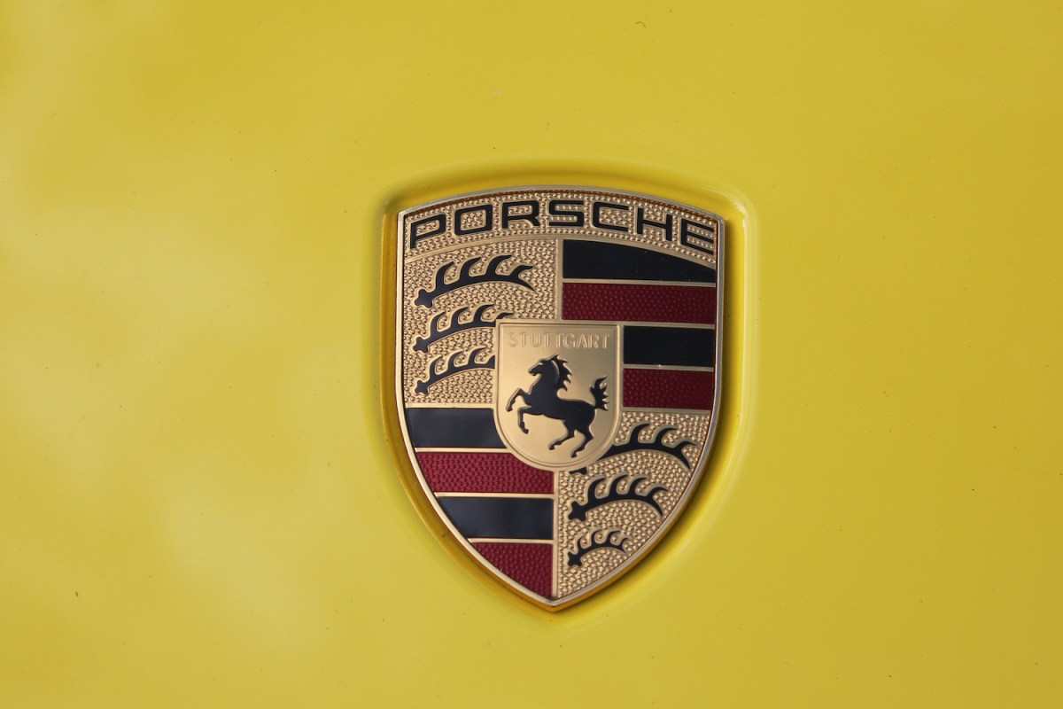Porsche crest logo set against a yellow background.