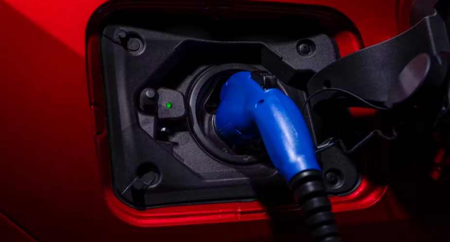 A red Toyota RAV4 Prime plug-in hybrid SUV is charging.