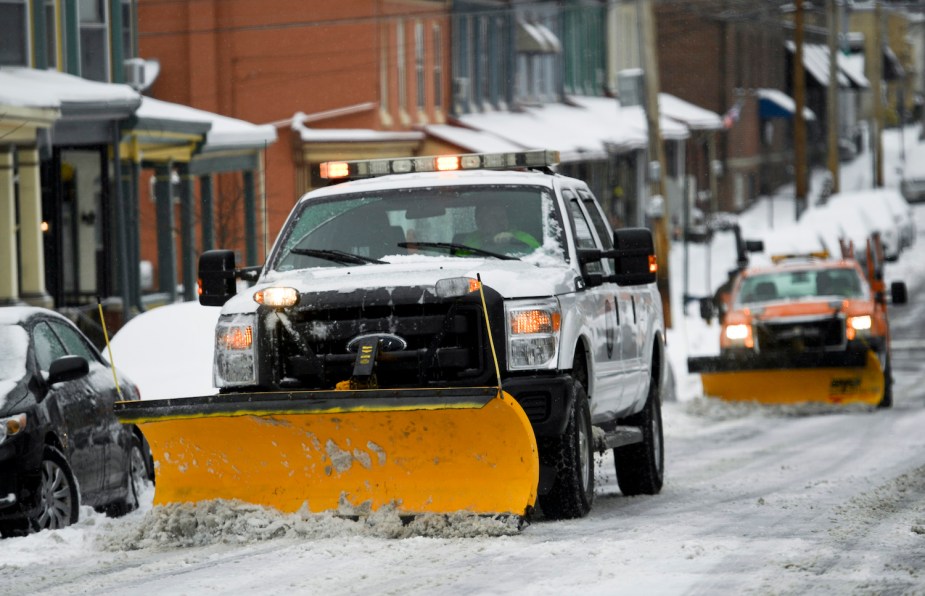 A Ford diesel truck plowing the main street of a small town on a cold winter day.