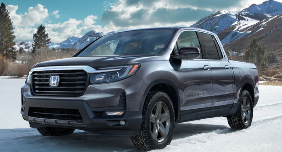 A gray 2023 Honda Ridgeline midsize pickup truck is parked in the snow. 