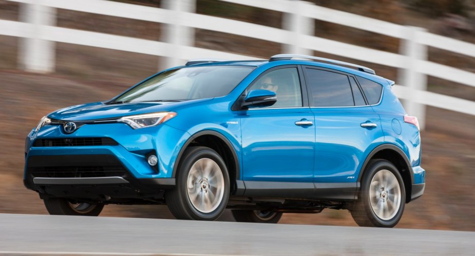 A blue 2016 Toyota RAV4 Hybrid small hybrid SUV is driving on the road. 
