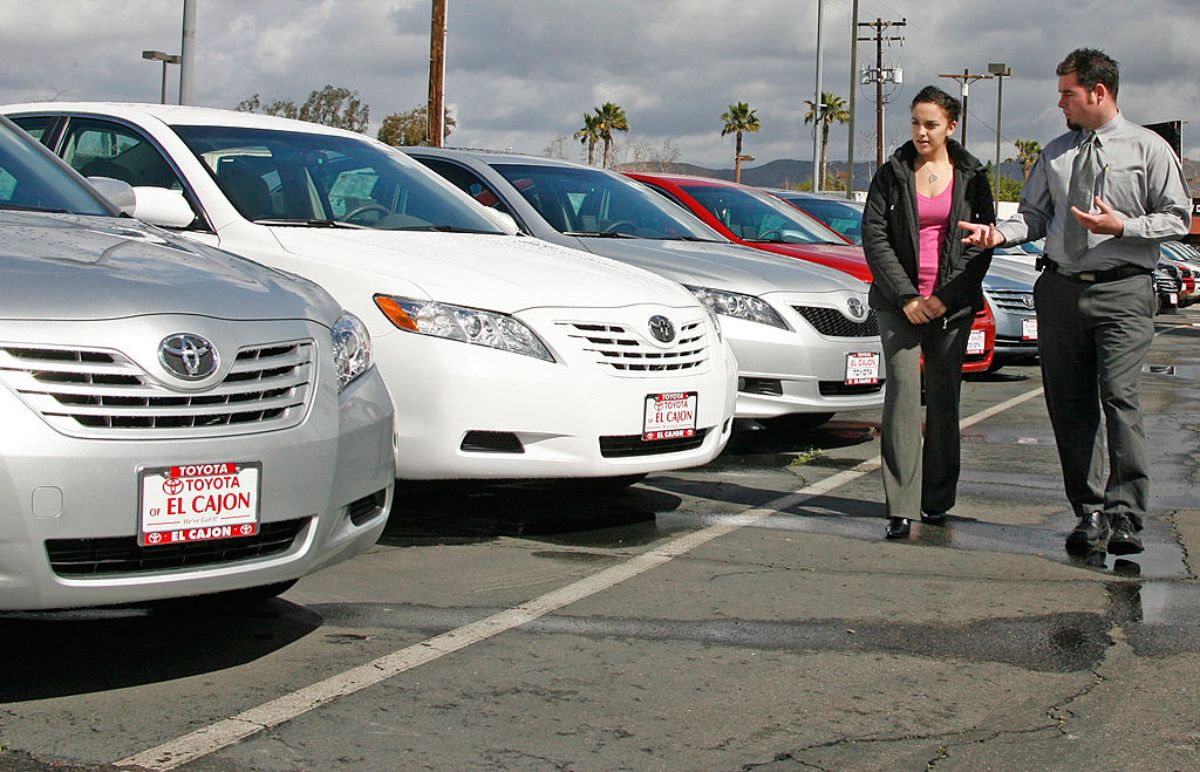 A car dealer showing used Toyota cars to a customer.