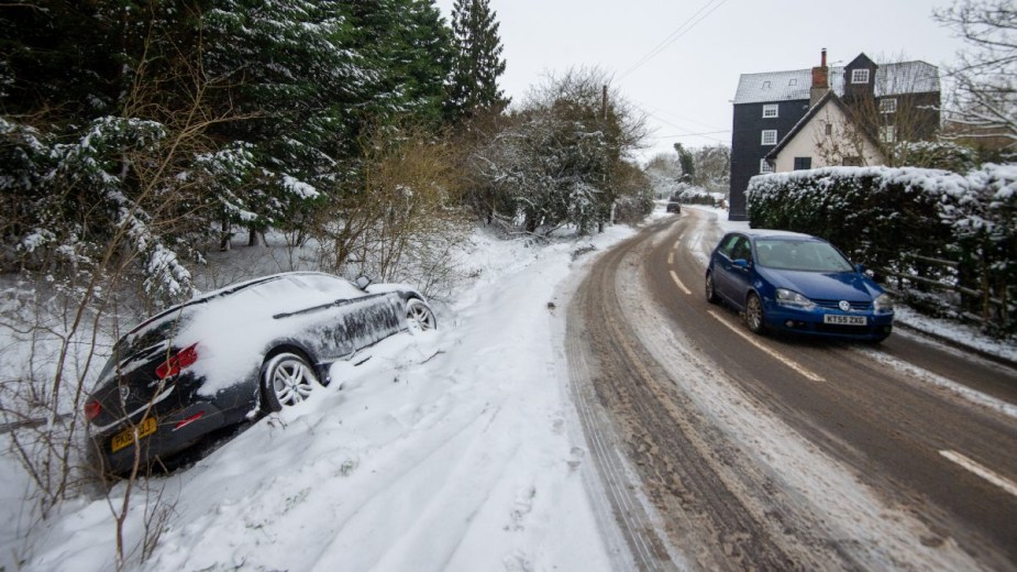 Vehicle stuck in snowy ditch, showing trick to correct slide on icy road to regain control of car 