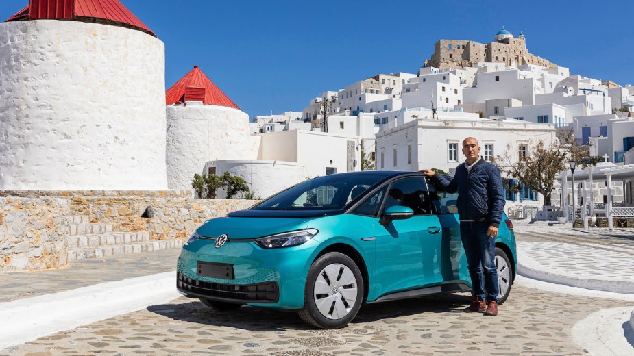 A greek island native posing next to his new Volkswagen ID.4 EV.