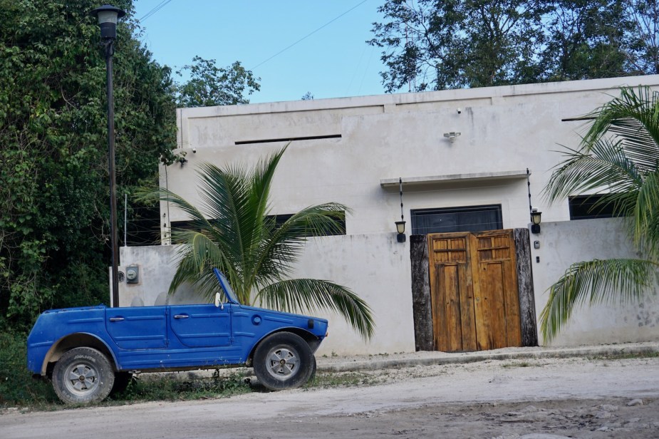 This is a Volkswagen Type 183 "Jeep" parked in front of a stucco house in Mexico.