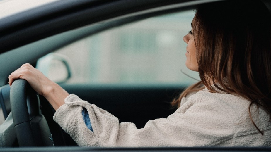 Woman maneuvering steering wheel, highlighting whether driving a car makes you smarter or dumber