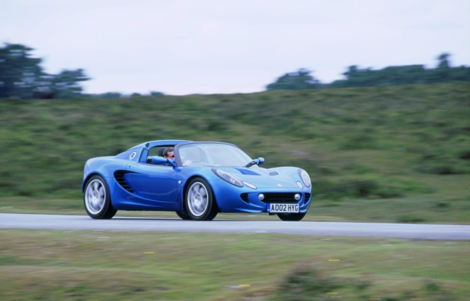A blue 2002 Lotus Elise driving down a road