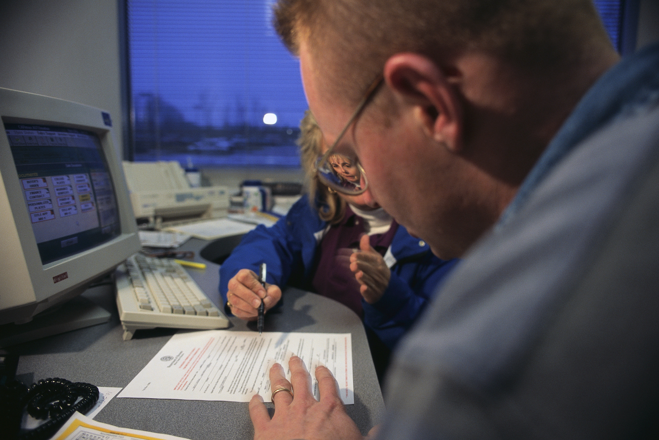 A CarMax sales rep helps a customer fill out paperwork.