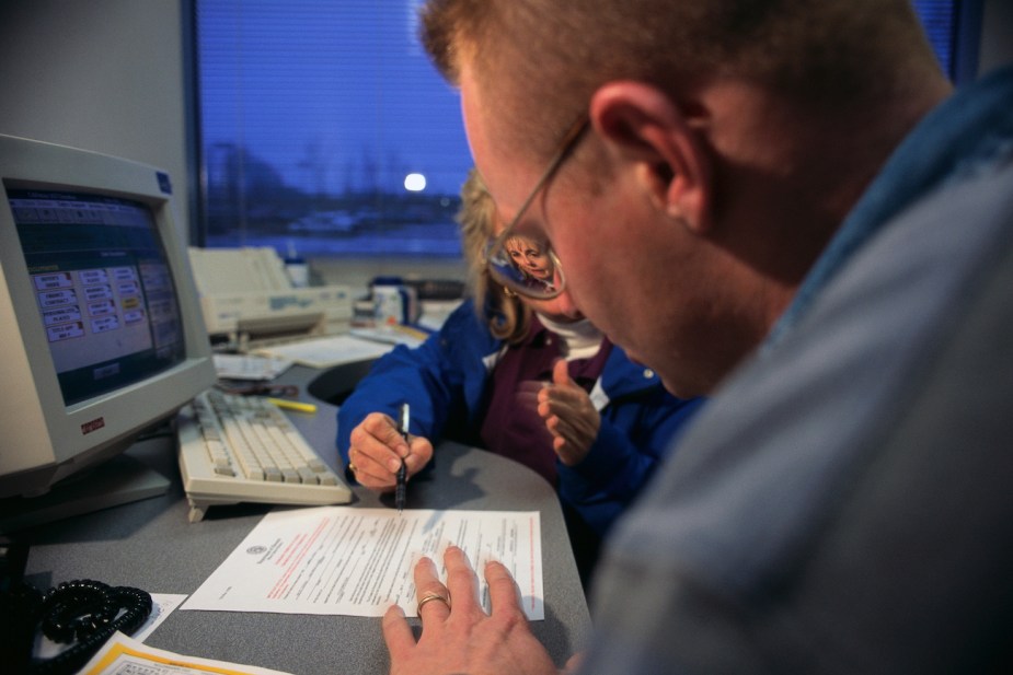 A CarMax sales rep helps a customer fill out paperwork.