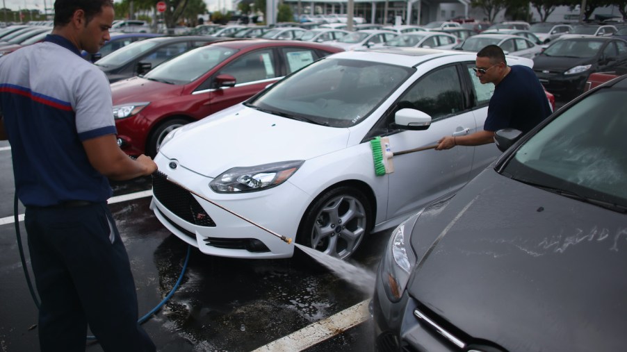 Dealership employees wash a car.