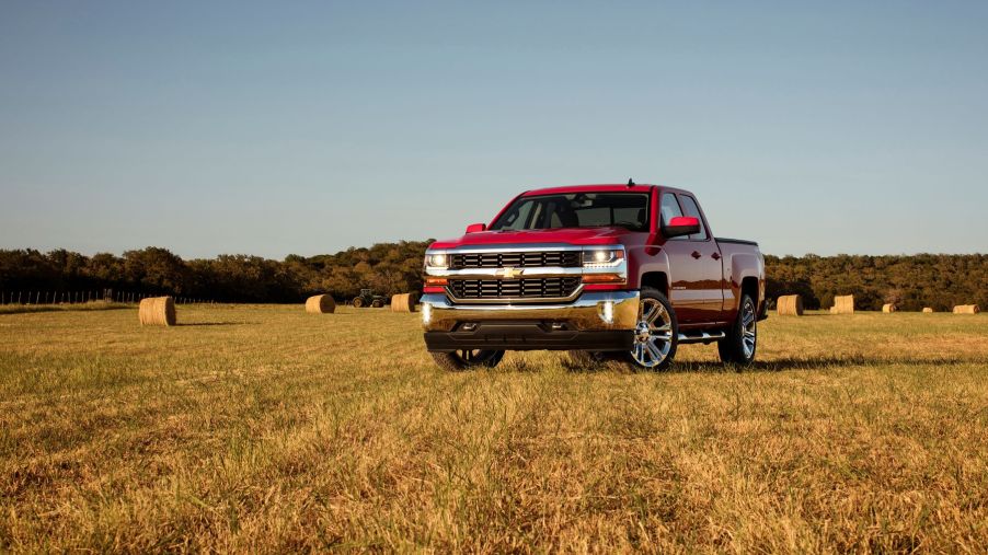 A red 2016 Chevrolet Chevy Silverado 1500 LT full-size pickup truck model parked on a farm hay field