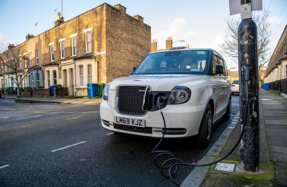 A plug-in electric Taxi EV plugged into a charging station on a residential street in London, England