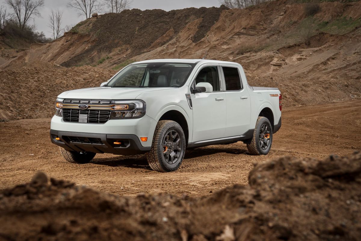 A white 2023 Ford Maverick Tremor compact pickup truck model parked near mounds of plowed dirt at a worksite