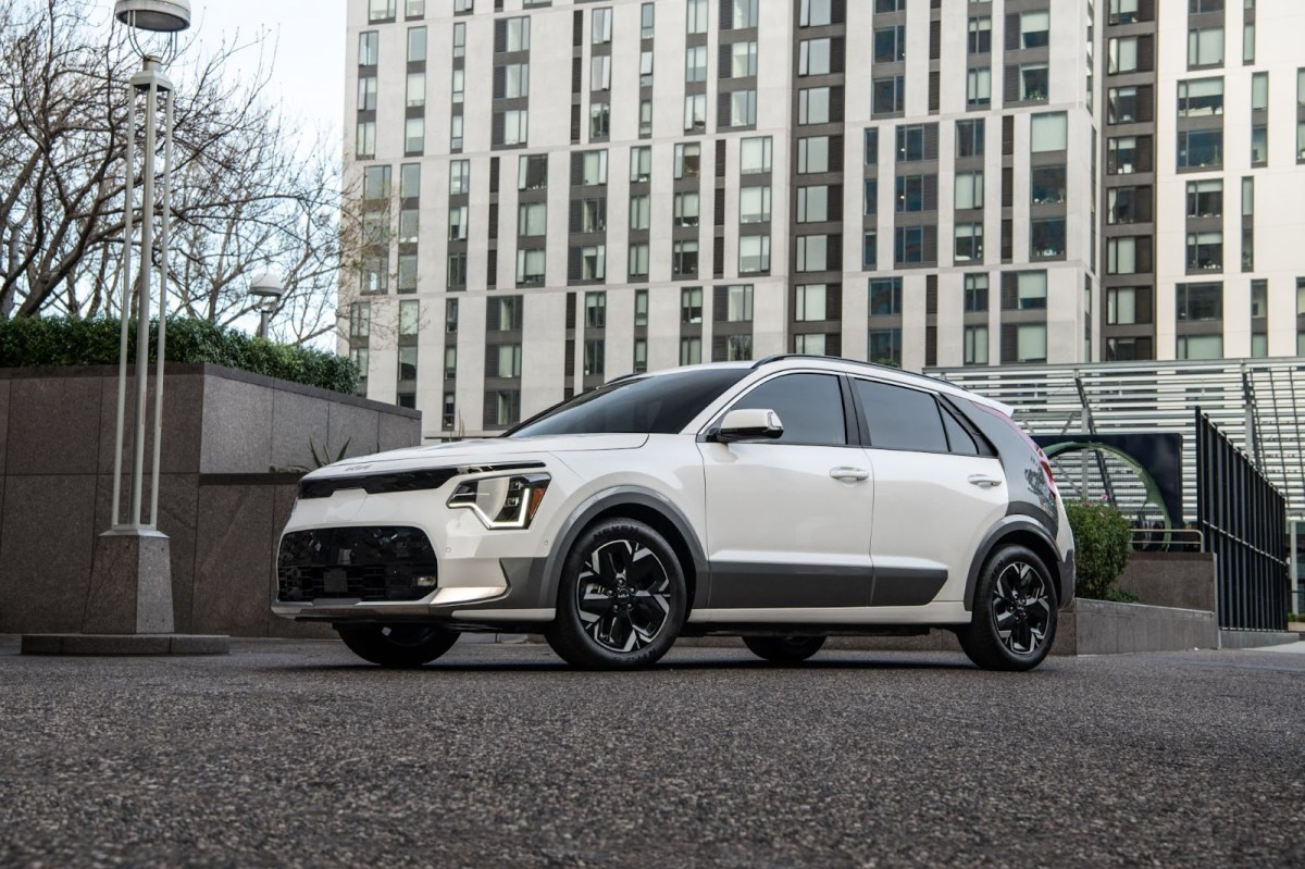 The 2023 KIA Niro EV in white, parked in front of a tall building.