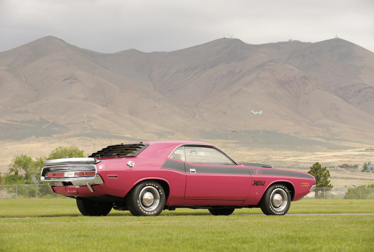 Reddish pink 1970 Dodge Challenger rare T/A Trans America trim parked in front of a mountain ridge.