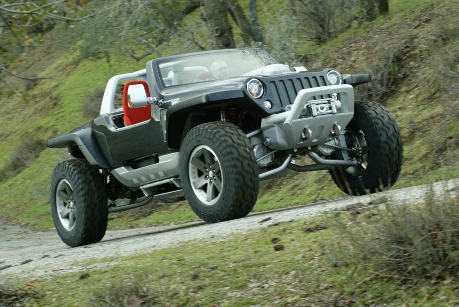 Black Jeep Wrangler Hurricane concept SUV with 4WD and four-wheel steer drives down a gravel road with a grassy slope visible in the background.