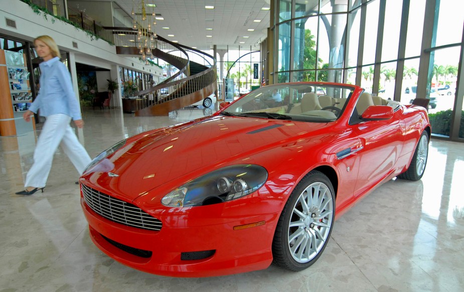 A bright red 2006 Aston Martin Db9 Volante convertible on a show room floor.