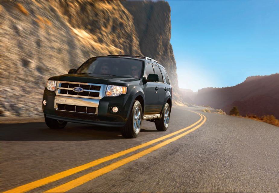 A 2009 Ford Escape compact crossover SUV model driving down a highway framed by rocky mountains