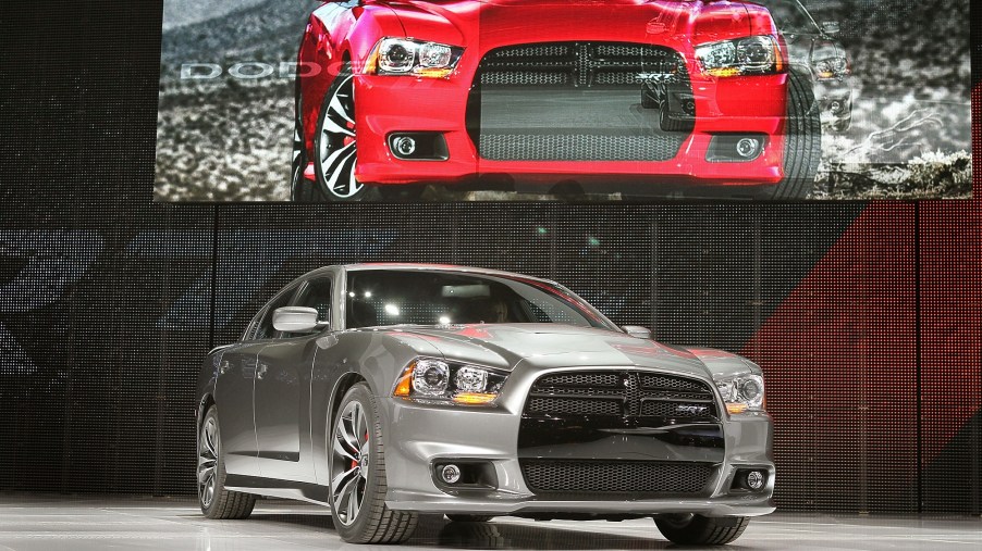 A gray 2013 Dodge Charger SRT8 poses on a stage at an auto show.