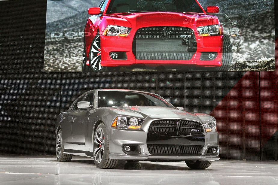 A gray 2013 Dodge Charger SRT8 poses on a stage at an auto show. 