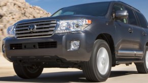 A blue 2013 Toyota Land Cruiser ifull-size SUV is driving on the road.