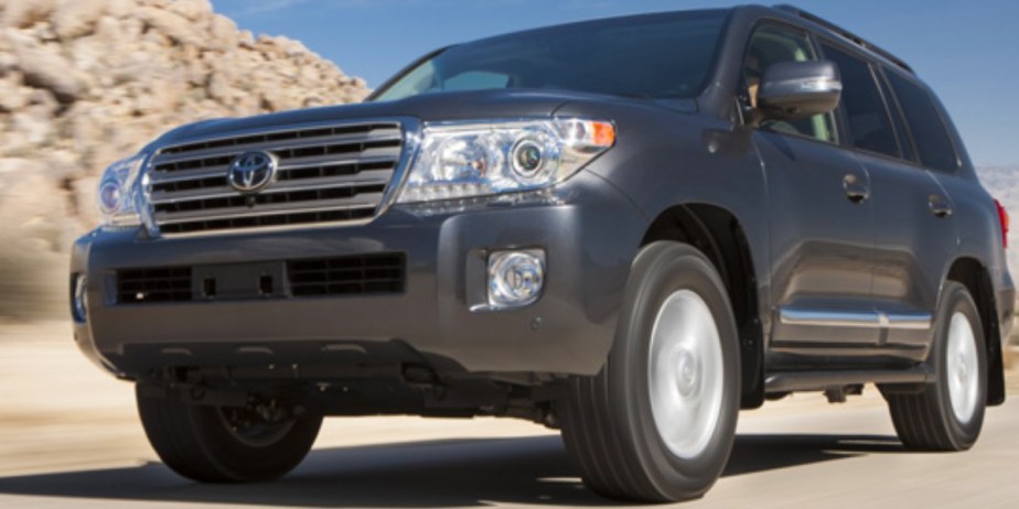 A gray 2013 Toyota Land Cruiser full-size SUV is driving on the road. 