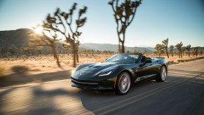A 2014 Chevrolet Corvette Stingray Convertible cruises down a desert road with the top down.
