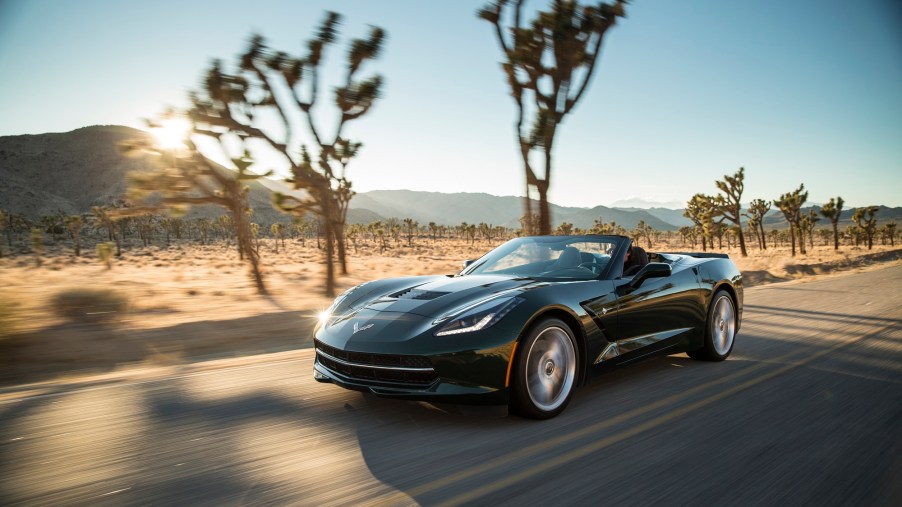 A 2014 Chevrolet Corvette Stingray Convertible cruises down a desert road with the top down.