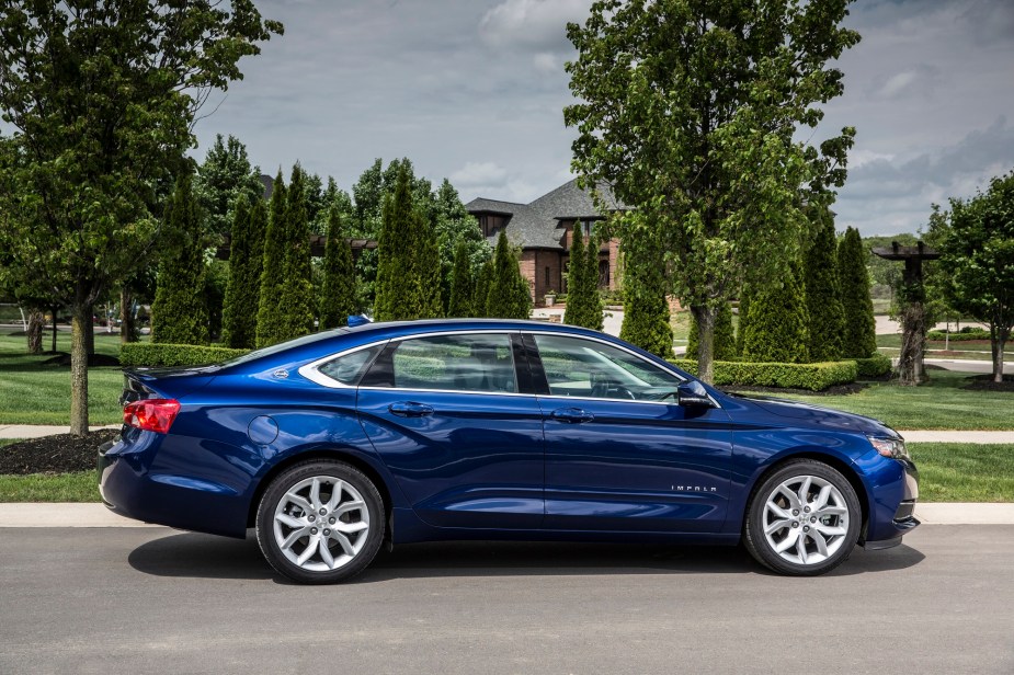 A blue Chevrolet Impala shows off its profile with contrast wheels.