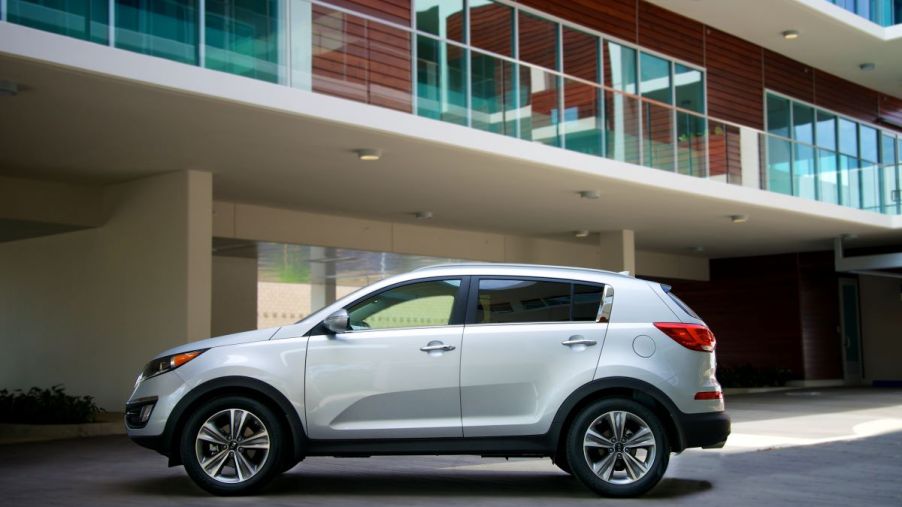 A 2015 Kia Sportage sits in a parking lot below an apartment building outlook