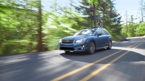 A blue Subaru hatchback drives down a road