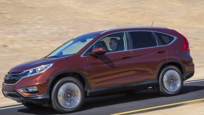 An orange 2016 Honda CR-V small SUV is driving on the road.