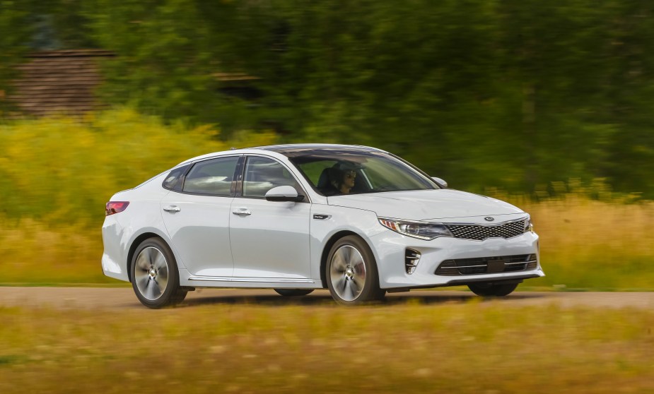 A white Kia Optima has no problems cornering on a back road without other cars.